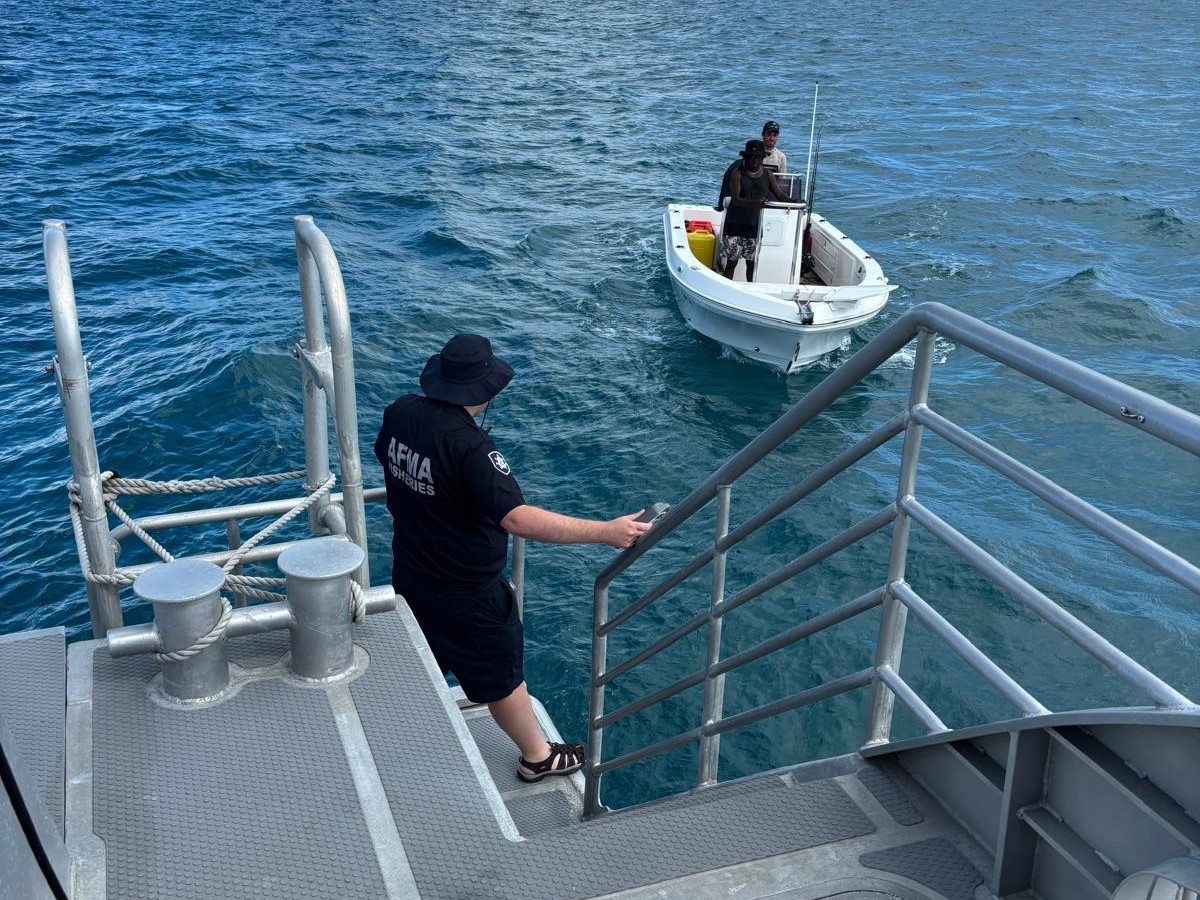 An AFMA fisheries officer hands a vessel monitoring system to a Torres Strait fisher